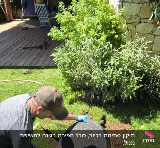 אדם פותח מכסה ביוב בגינה